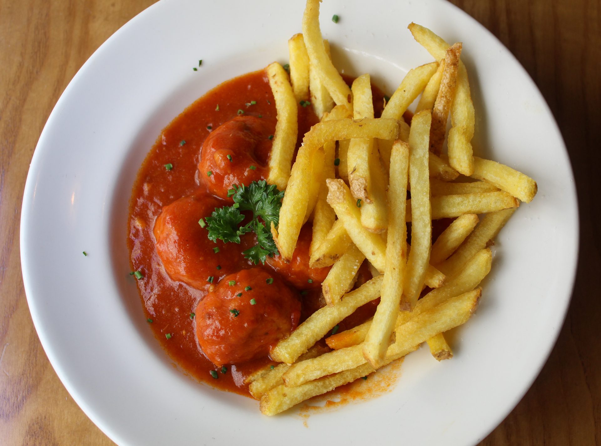 Albóndigas de pollo y espinacas estofadas acompañadas de patatas fritas