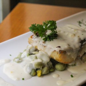 Corvina sobre lecho de habitas y cebolleta con salsa de cítricos